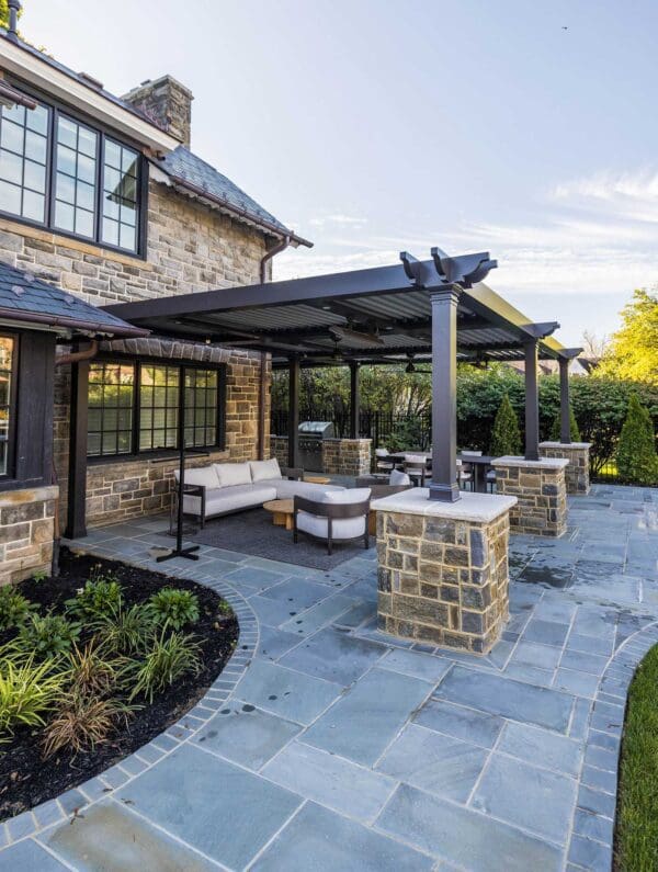 photo of backyard bluestone patio, stone columns and outdoor kitchen wrapping the pool