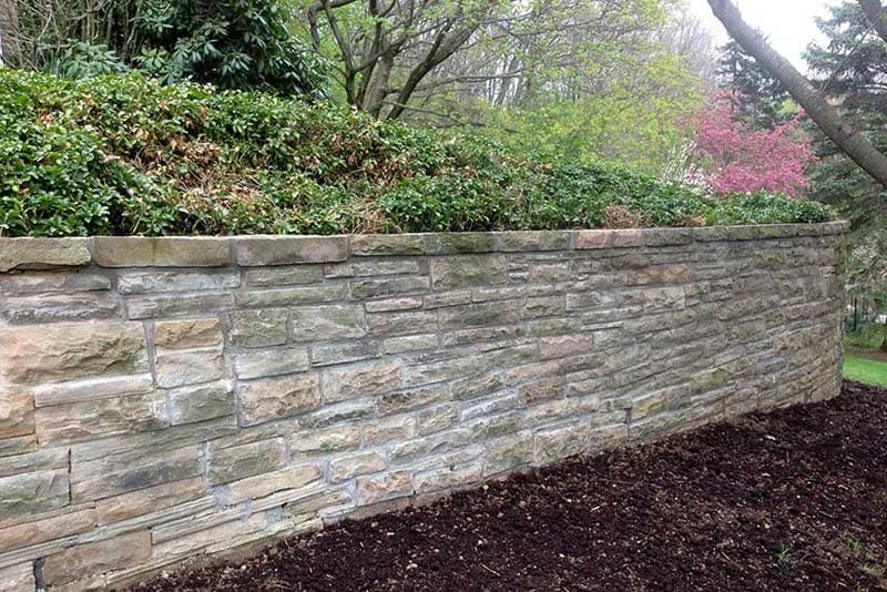 natrual-stone-retaining-wall-installation-wichman-1 photo of natrual stone retaining wall in backyard