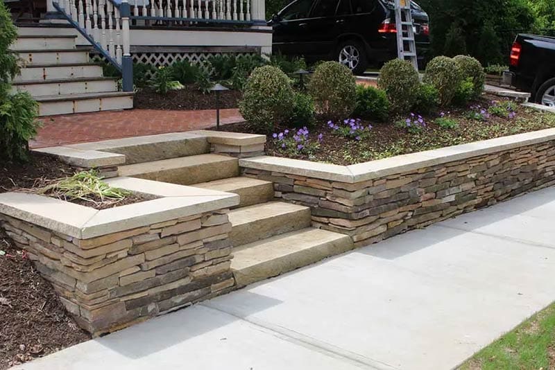 photo of natural stone retaining wall along a front sidewalk in Pittsburgh installed by Wichman Landscape